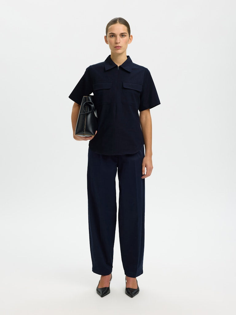 Person wearing a navy outfit with a black bag on a white background